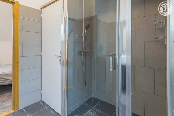 Une salle de bain moderne avec une douche à parois de verre, des murs carrelés et une porte en bois.