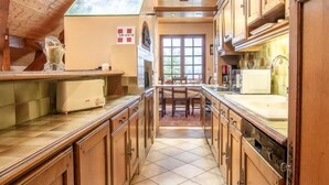 A narrow kitchen with wooden cabinets, a tiled floor, and a skylight.