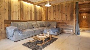 Ein gemütliches Wohnzimmer mit einem Ecksofa, einem Holztisch und einer Pendelleuchte.