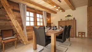 Ein Essbereich mit Holztisch, schwarzen Stühlen und einem Schrank in einem rustikalen Blockhaus.
