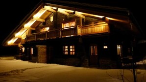 Ein großes, mehrstöckiges Holzhaus mit ausgeprägtem Dachboden und Gauben, umgeben von Schnee.