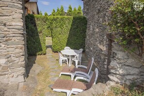 A stone-walled outdoor patio with a round table and chairs, surrounded by neatly trimmed hedges. - LE BOUQUETIN - SAINT ANDRE (SAINT ANDRE)