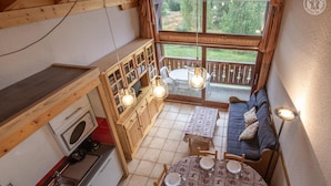 A compact kitchen with wooden cabinets, a built-in oven, and a dining area with a round table and chairs. - CRISTAL 4 - HAUTELUCE LES SAISIES (HAUTELUCE LES SAISIES)