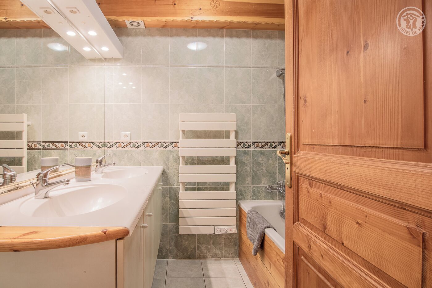 Une salle de bain avec un meuble-lavabo en bois, un lavabo avec un miroir et un espace douche.