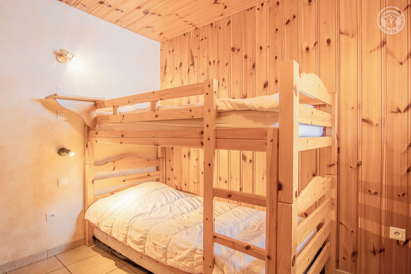 Une chambre avec des lits superposés, des murs en bois et un plafond blanc.