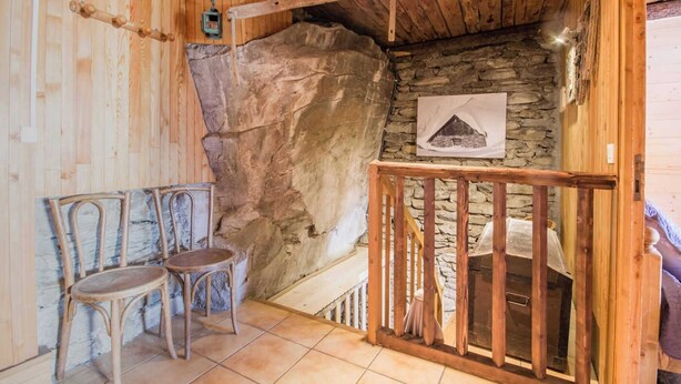 Une pièce rustique avec des murs en pierre et des éléments en bois, comprenant un banc en bois et une petite table en bois.