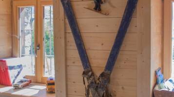 Un intérieur en bois, avec une grande structure de poutres apparentes au plafond, une petite fenêtre et un banc en bois.