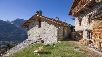 Un bâtiment en pierre doté d’un balcon en bois, entouré de montagnes.