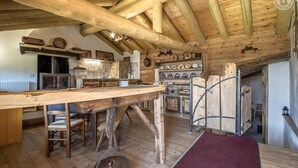 A rustic kitchen with wooden beams, a large table, and a red rug. - LA CHIRA - VAL CENIS (VAL CENIS)
