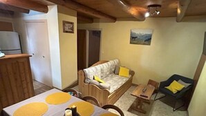 A cozy room with a wooden ceiling, a sofa, a small table with yellow placemats, and a chair.