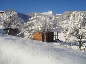 A snow-covered landscape with a wooden cabin and a mountain in the background.