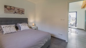Un dormitori amb llit, taulella de nit, làmpada i un quadre a la paret.