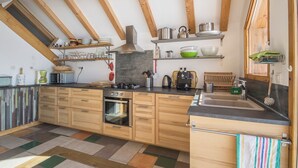 Eine moderne Küche mit Holzausstattung, einem eingebauten Backofen und verschiedenen Küchenutensilien in Regalen.