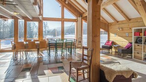 Eine Holzhütte mit Essbereich, Sitzgelegenheiten und Blick auf eine verschneite Landschaft.