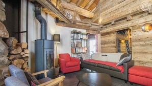A cozy log cabin interior with a fireplace, seating area, and bookshelves.