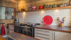 A kitchen with a stove, a red circular object on the wall, and various kitchen items on the countertop.