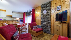 Ein gemütliches Wohnzimmer mit roten Sofas, einem Holztisch und einer Steinwand.