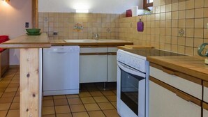 Eine kompakte Küche mit Geschirrspüler, Backofen und einer kleinen Kochinsel mit Spüle.