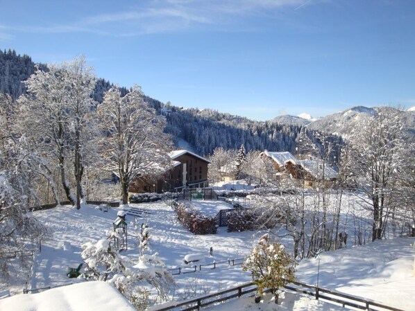 A snow-covered landscape with a wooden cabin and trees.