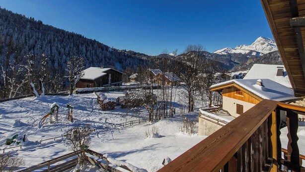 Un paysage de montagne enneigé, avec un chalet en bois et un télésiège au premier plan.