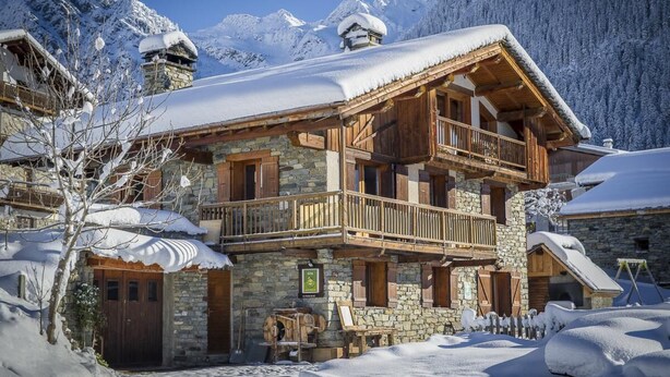 A chalet-style building with a stone facade, wooden balconies, and a snow-covered roof, surrounded by mountains. - LA CHARMETTE - LA ROSIERE MONTVALEZAN (LA ROSIERE MONTVALEZAN)