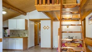 Interior de madeira com quarto em mezanino, cozinha e sala de estar.