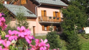 A two-story wooden building with a balcony, surrounded by greenery and flowers. - CHALET L'ANDORSE - VALLOIRE (VALLOIRE)
