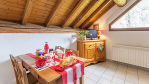 A cozy dining area with a wooden table set for a meal, a wooden cabinet with a heart-shaped decoration, and a window providing natural light. - CHALET L'ANDORSE - VALLOIRE (VALLOIRE)
