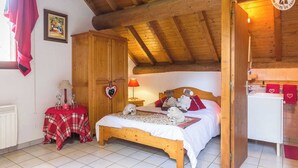 A cozy bedroom with a wooden bed, a red plaid table, a heart-shaped decoration, and a small nightstand with a lamp. - CHALET L'ANDORSE - VALLOIRE (VALLOIRE)