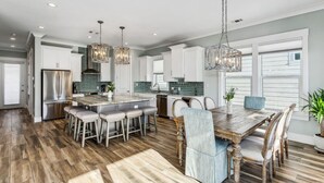 A modern kitchen with a central island, bar stools, and pendant lighting. - Calla Lily Cove : Breathtaking Home w/Elevator In a Gated Community-Sleeps 12 (Navarre)