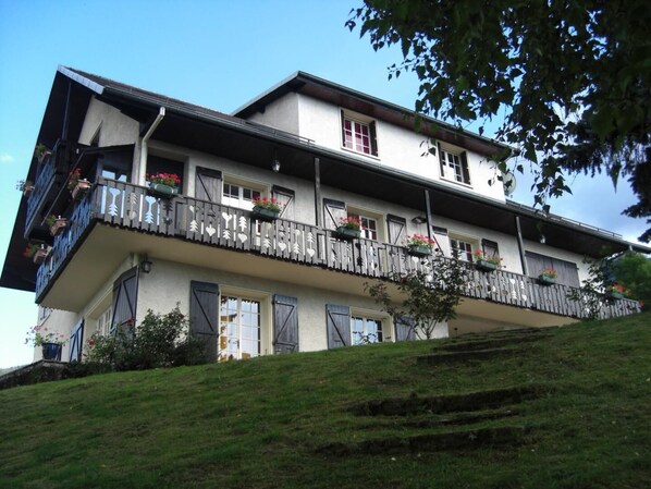 A two-story building with a balcony on the upper floor, featuring a railing with heart-shaped decorations and flower boxes.