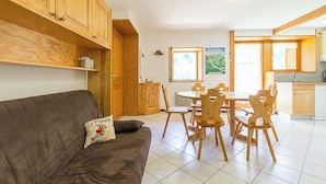 Un salon chaleureux avec un canapé marron et une table à manger en bois, entourée de chaises.