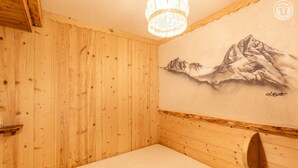A wooden room with a bed, a wooden headboard, and a wall with a mountain painting. - LA METAIRIE DE MON PERE (LE PLANAY)