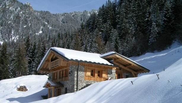 A wooden cabin with a stone foundation, set on a snow-covered slope with a forest backdrop. - LA METAIRIE DE MON PERE (LE PLANAY)