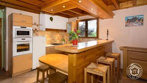 A kitchen with wooden cabinets, a built-in oven, a stove, and a bar area with stools.