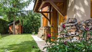 A rustic wooden building with a stone wall and a neatly trimmed lawn.