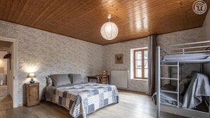 A cozy room with a wooden ceiling, a bed with a patterned quilt, a bunk bed, a table, and a window with curtains. - CHEZ ROSALIE - LA BIOLLE (LA BIOLLE)