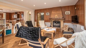 A cozy living room with a fireplace, wooden furniture, and a television. - CHEZ ROSALIE - LA BIOLLE (LA BIOLLE)