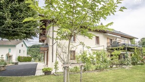 A two-story house with a balcony, surrounded by greenery and a paved driveway. - CHEZ ROSALIE - LA BIOLLE (LA BIOLLE)