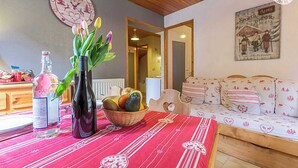 A cozy living room with a wooden ceiling, a red tablecloth with heart patterns, a vase with flowers, a bottle, and a fruit basket. - LE BOUQUETIN - VAL CENIS (VAL CENIS)