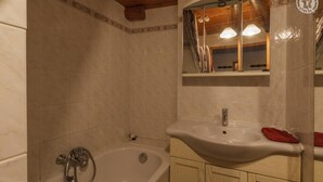 A bathroom with a bathtub, a sink, and a mirror. - LES COLOMBIERES - MÉSANGE (BONNEVAL SUR ARC)