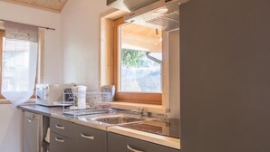 Une cuisine moderne avec des meubles de couleur sombre, un évier en acier inoxydable et une fenêtre qui laisse entrer la lumière naturelle.