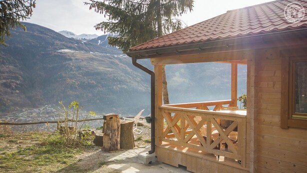 Une cabane en bois dotée d’un balcon donnant sur un paysage montagneux.
