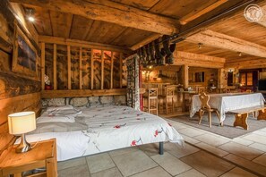 Ein rustikaler Raum mit Holzboden, einem Bett, einem Esstisch und einer Bar.