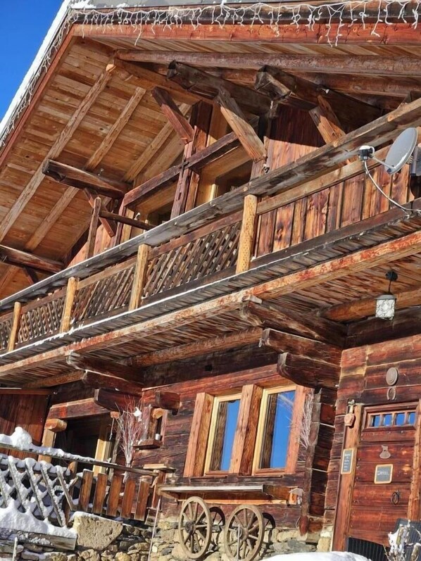 Eine Holzhütte mit Balkon, Steinfundament und rustikalem Äußeren.