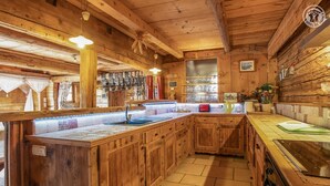 A rustic kitchen with wooden cabinets, a central island with a sink, and a stove. - LA FERME D'EUGENIE - FLUMET (FLUMET)