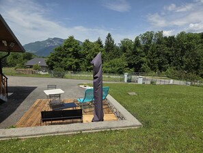 Un'area patio con tavolo e sedie, un pontile in legno e un vaso in pietra.