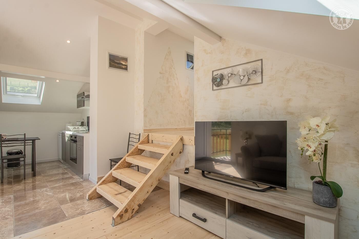 Un salon moderne avec un escalier en bois, un téléviseur à écran plat et une orchidée en pot.