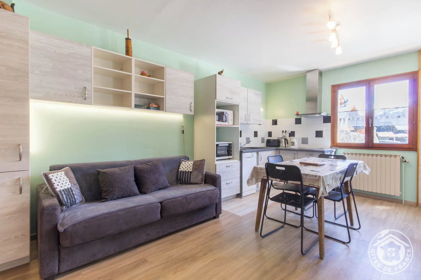 Un espace de vie compact comprenant un canapé, une table à manger et une kitchenette.