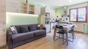A compact living space with a sofa, dining table, and kitchenette. - LES RUFFES - LES BELLEVILLE (LES BELLEVILLE)